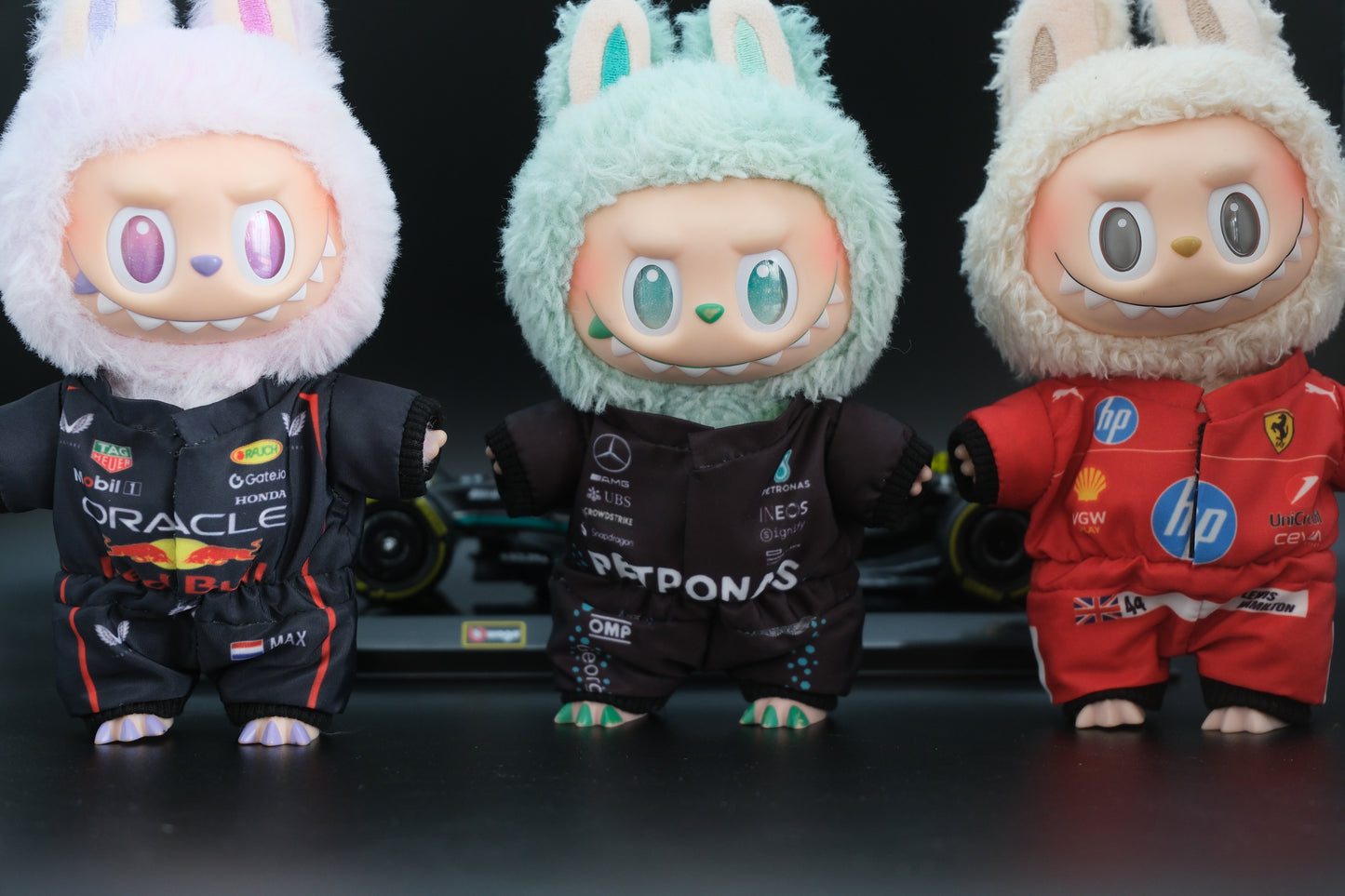 A collection of four LABUBU dolls wearing handmade F1 team uniforms from Mercedes, Ferrari, and Red Bull Racing.