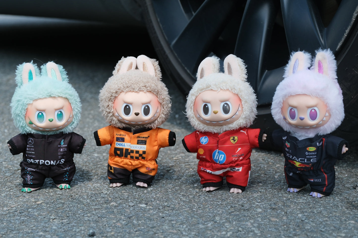 A collection of four LABUBU dolls wearing handmade F1 team uniforms from Mercedes, McLaren, Ferrari, and Red Bull Racing.
