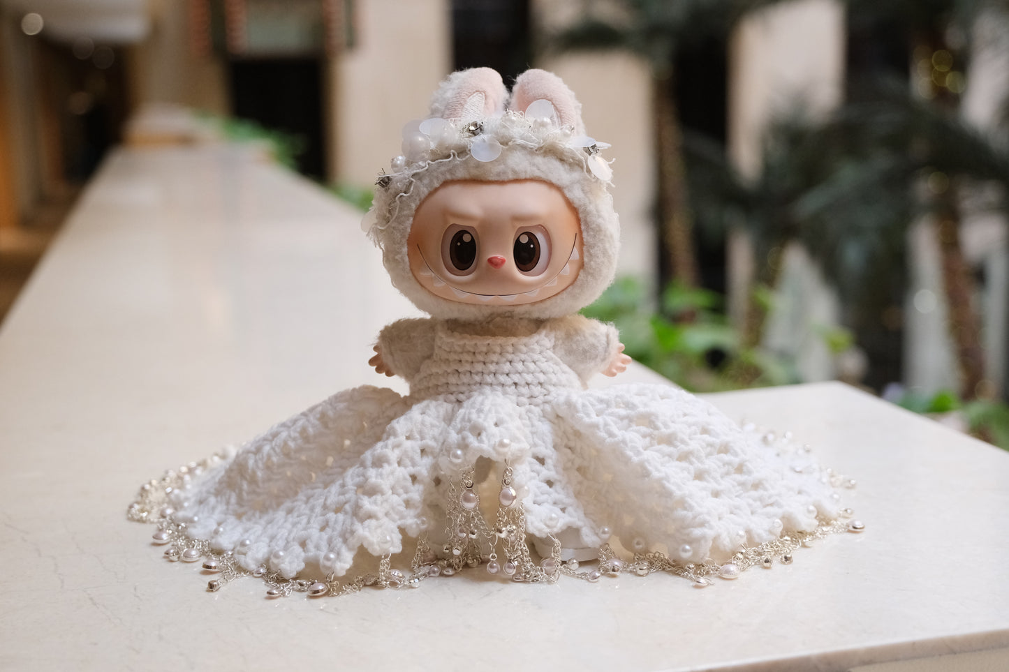 A Labubu figure wearing a white wedding dress with a lace bodice, full skirt, and a headband.