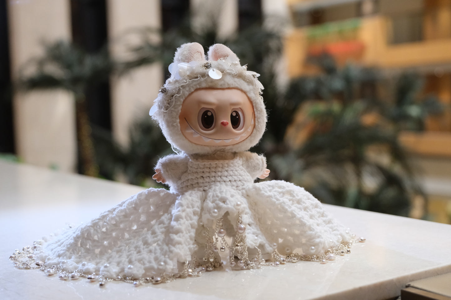 A Labubu figure wearing a white wedding dress with a lace bodice, full skirt, and a headband.