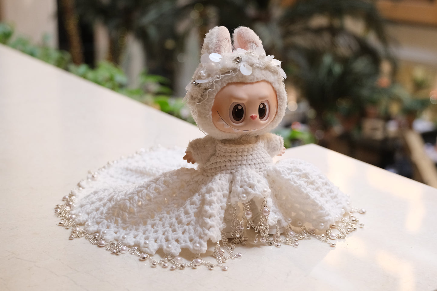 A Labubu figure wearing a white wedding dress with a lace bodice, full skirt, and a headband.