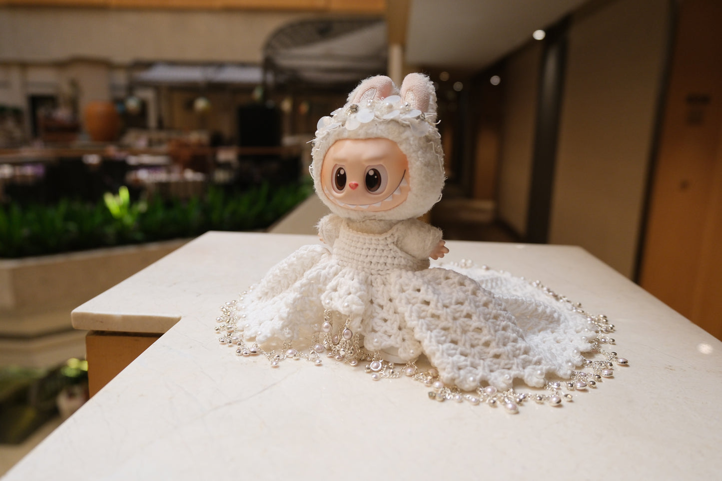 A Labubu figure wearing a white wedding dress with a lace bodice, full skirt, and a headband.