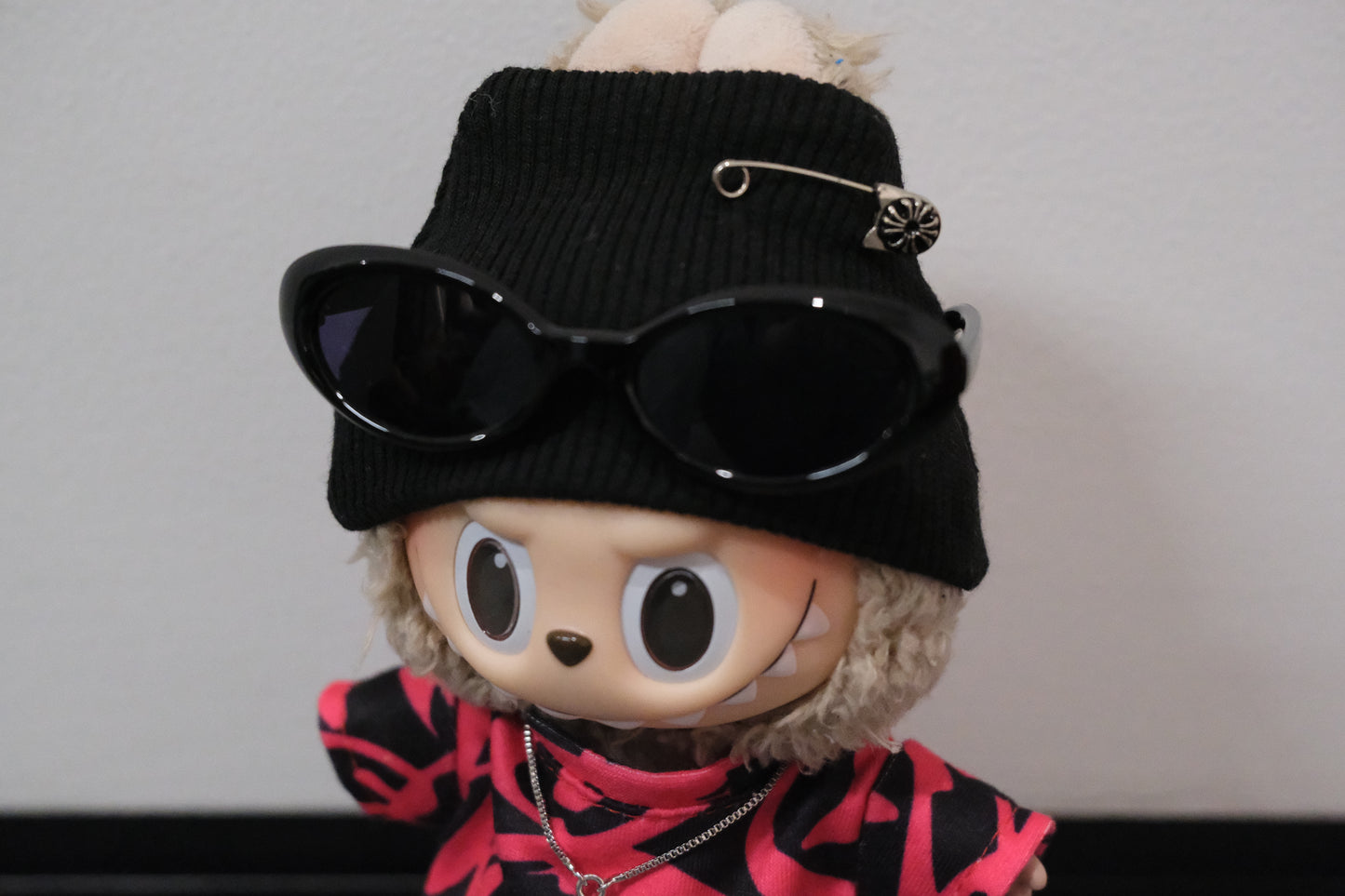 labubu wearing a black beanie with sunglasses and a pink and black outfit