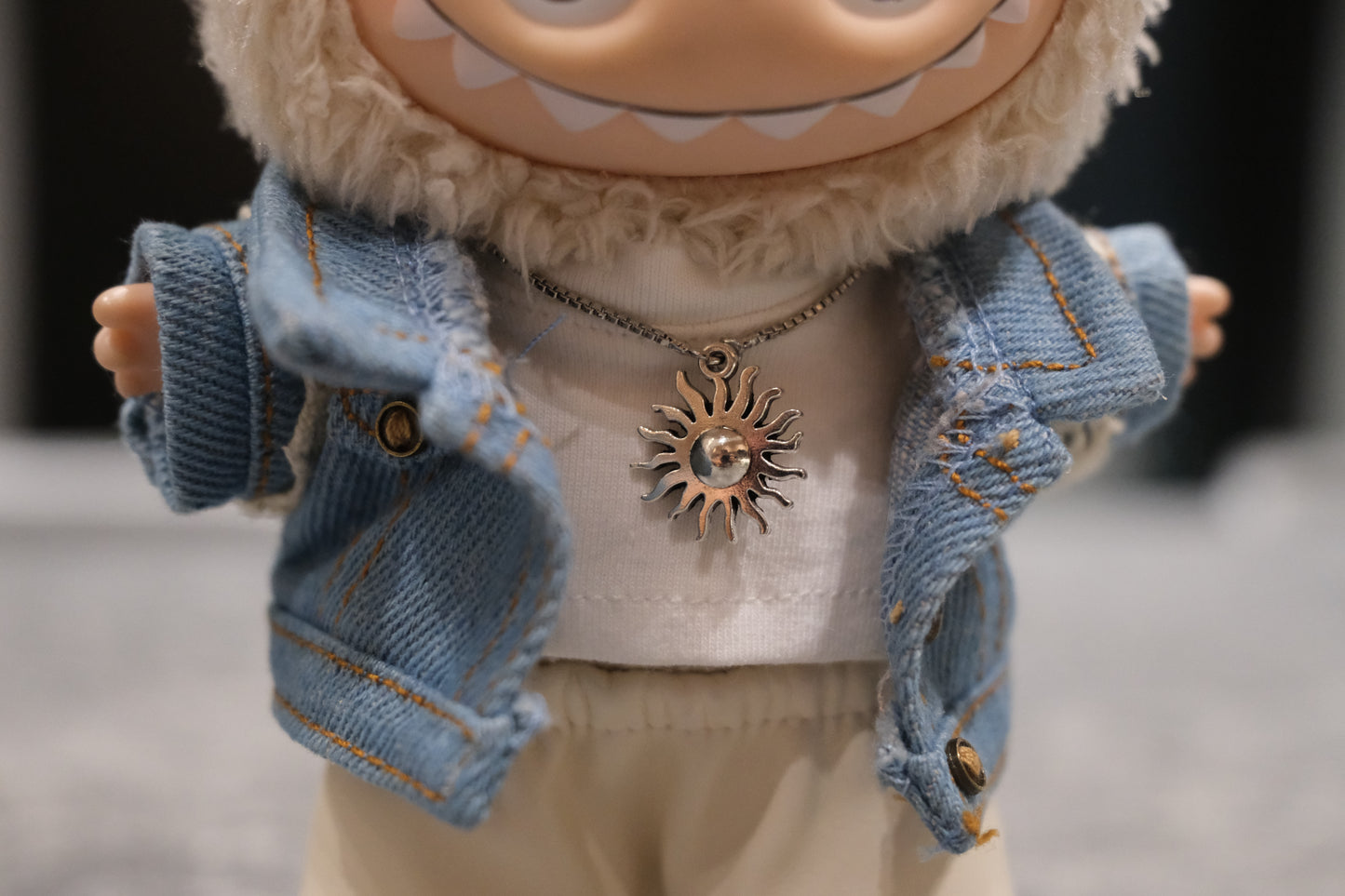 Detailed view of the Labubu figure's sun necklace and faux leather pants.