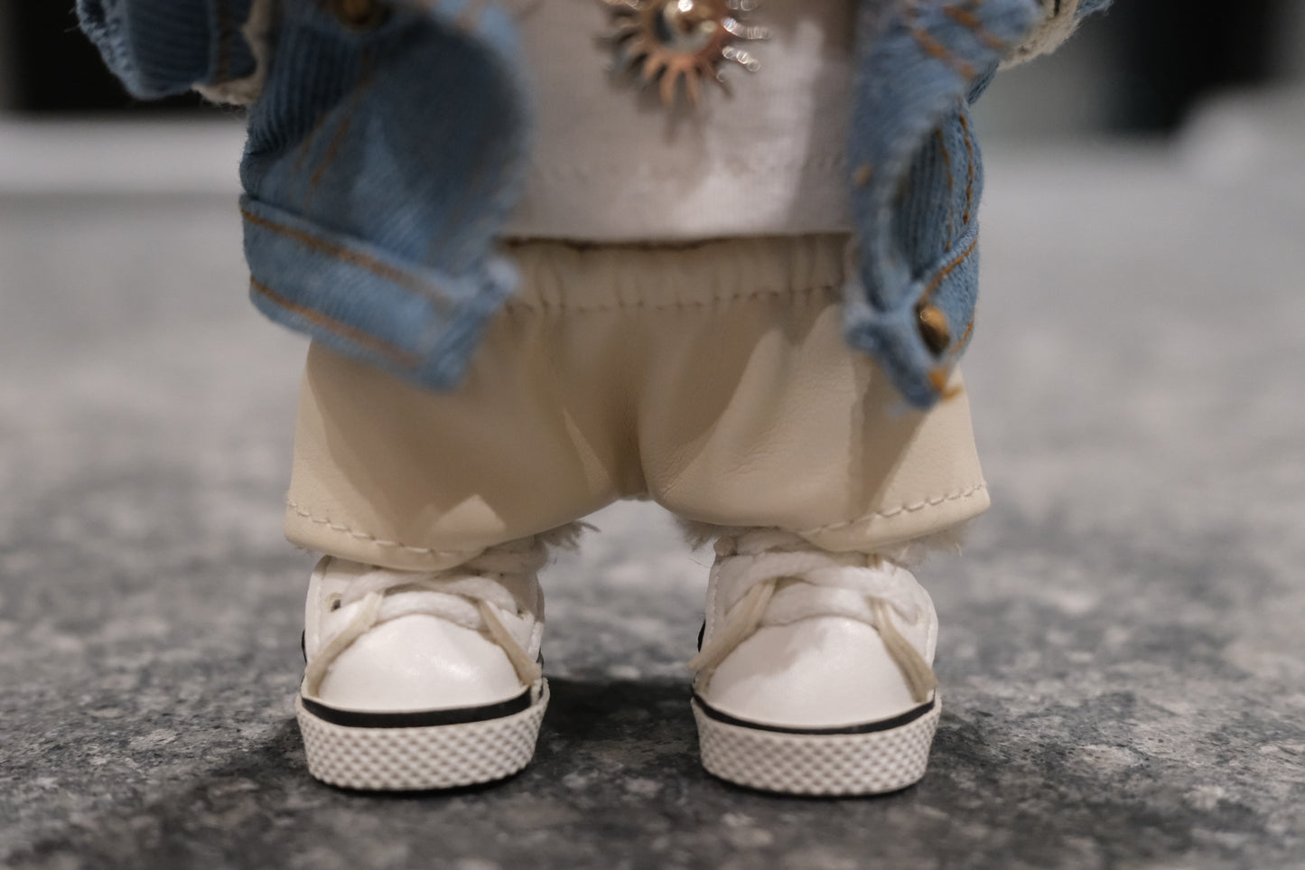 Detailed view of the Labubu figure's sun necklace and faux leather pants.