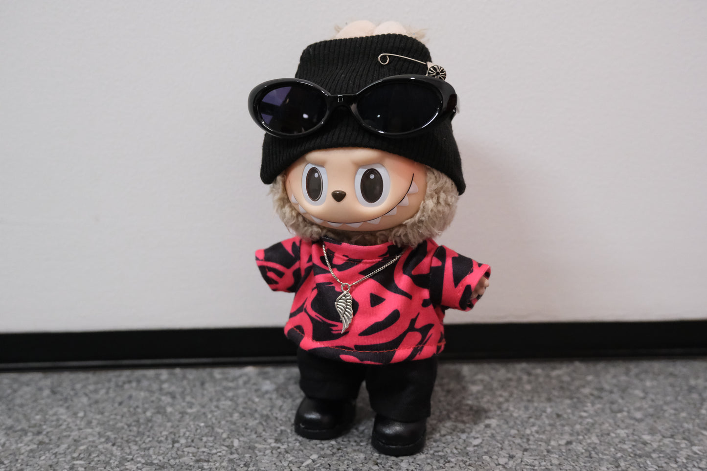 Toy figure wearing sunglasses, black hat, and pink and red patterned shirt