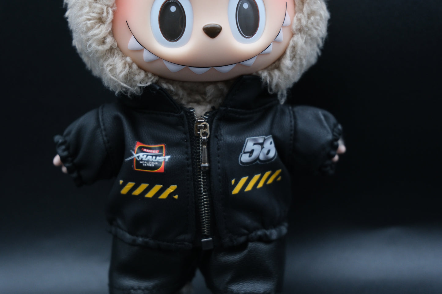 A close-up of Labubu designer toy figure in a dark, urban-style outfit, featuring a black leather jacket and pants , sunglasses and a pair of shoes