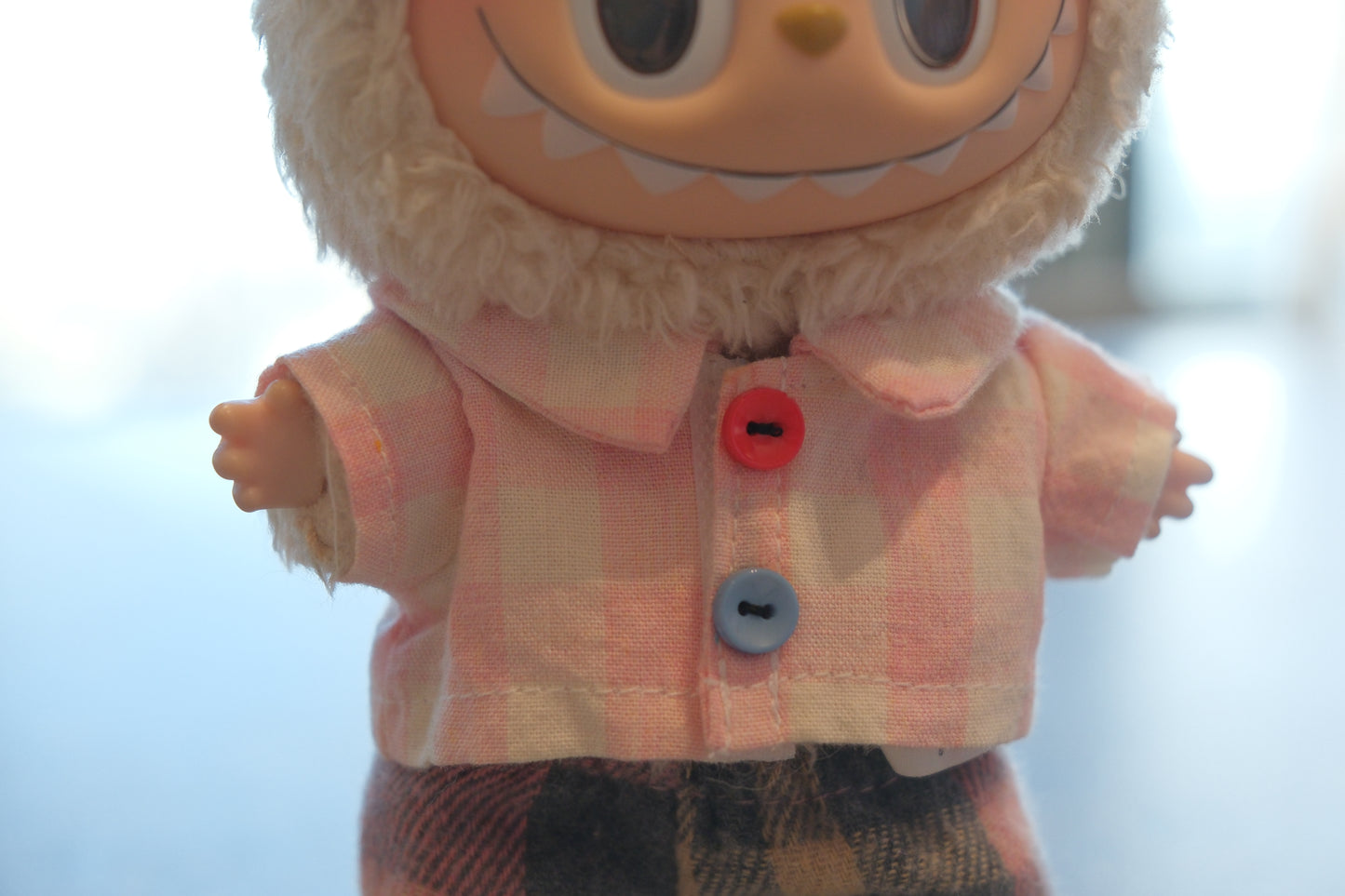 Labubu figure wearing a 4-piece outfit with a pink gingham shirt, dark plaid pants, white sneakers, and pink glasses