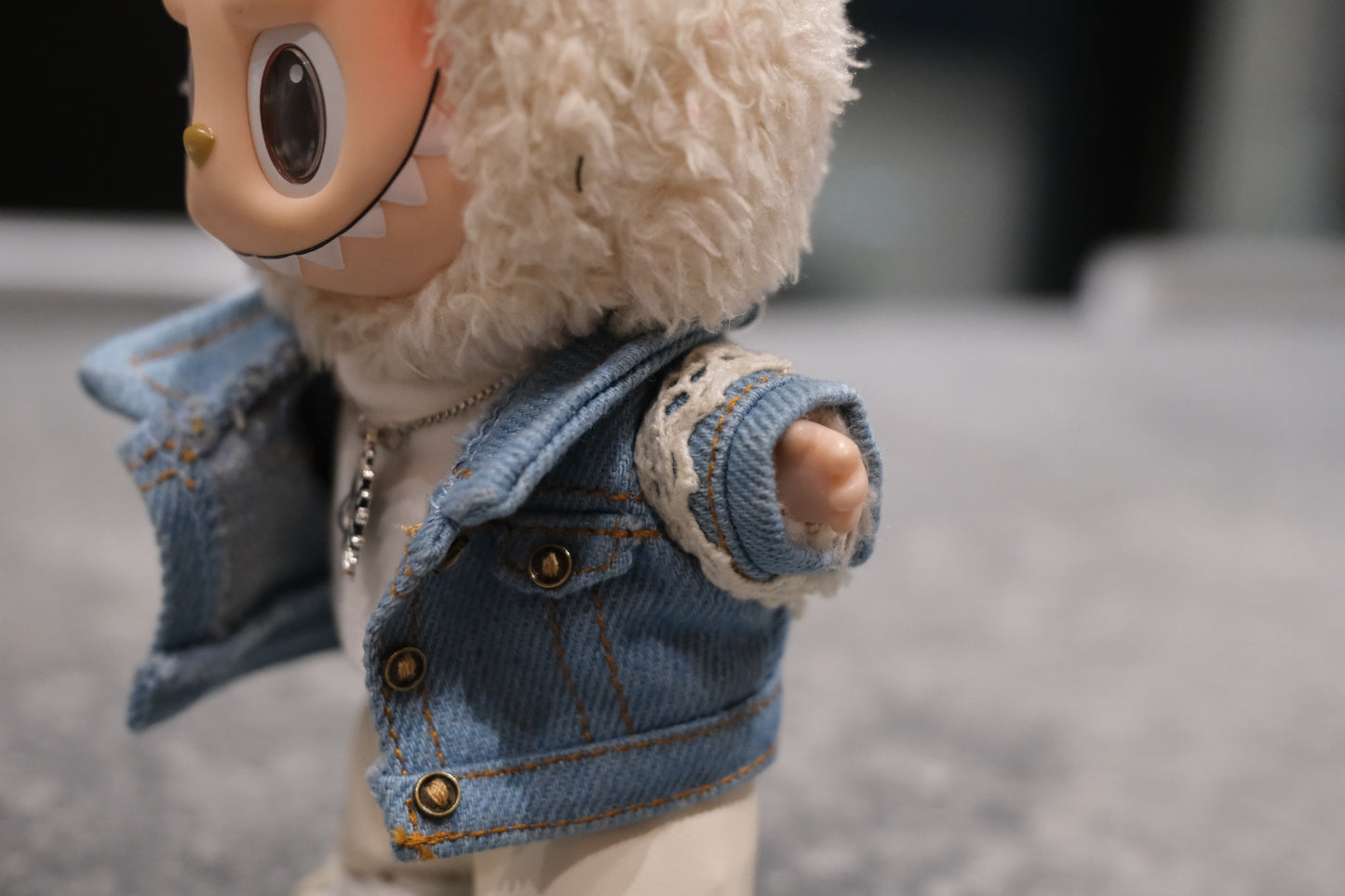 Labubu figure wearing a 5-piece outfit: light blue denim jacket, white tee, white leather shorts, sun necklace, and sneakers