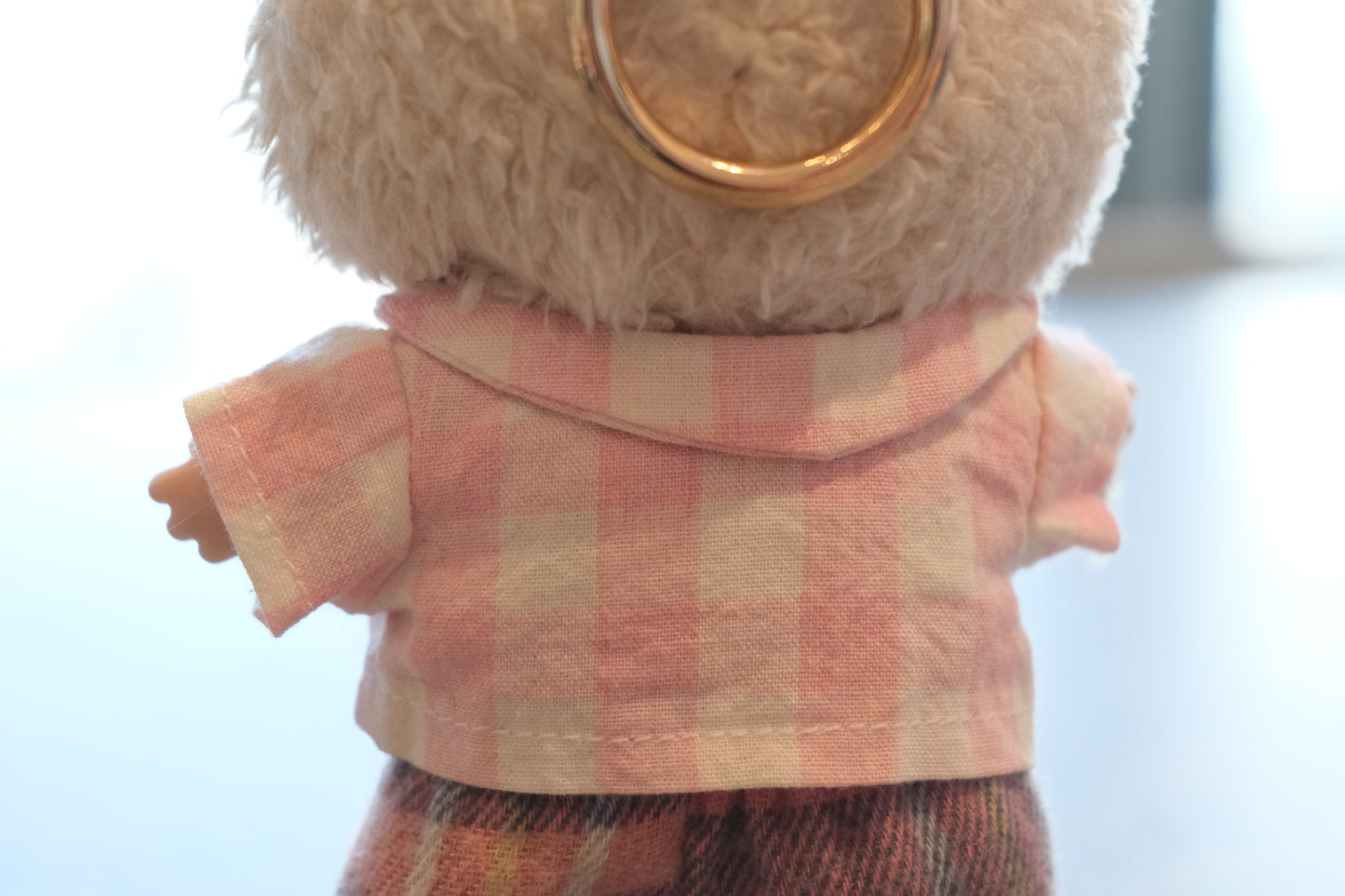 Close-up of The Monsters figure's pink gingham shirt, mismatched buttons, and cozy flannel pants