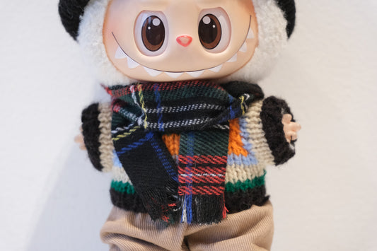 Close-up of labubu figure's high-contrast Argyle knit scarf, sweater and black beanie.