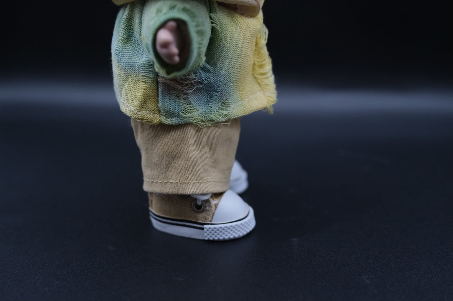 details of labubu wearing distressed tie-dye hoodie, khaki pants