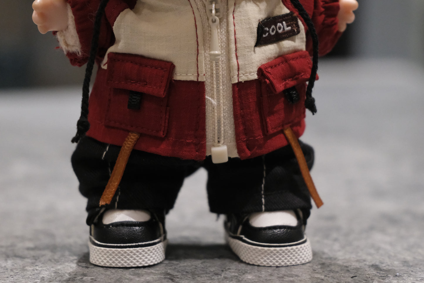 Close-up of The Monsters figure's red utility jacket with "COOL" patch and pockets.