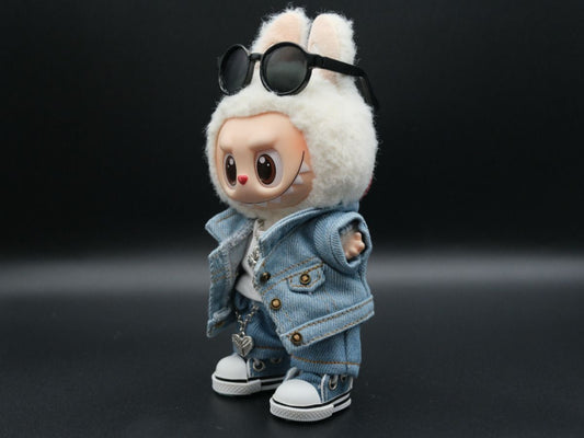 A side view of a Labubu doll wearing a denim jacket, jeans, and a white t-shirt. The doll's sunglasses are propped on its white fuzzy hood, and its hand is visible with a slight wave.