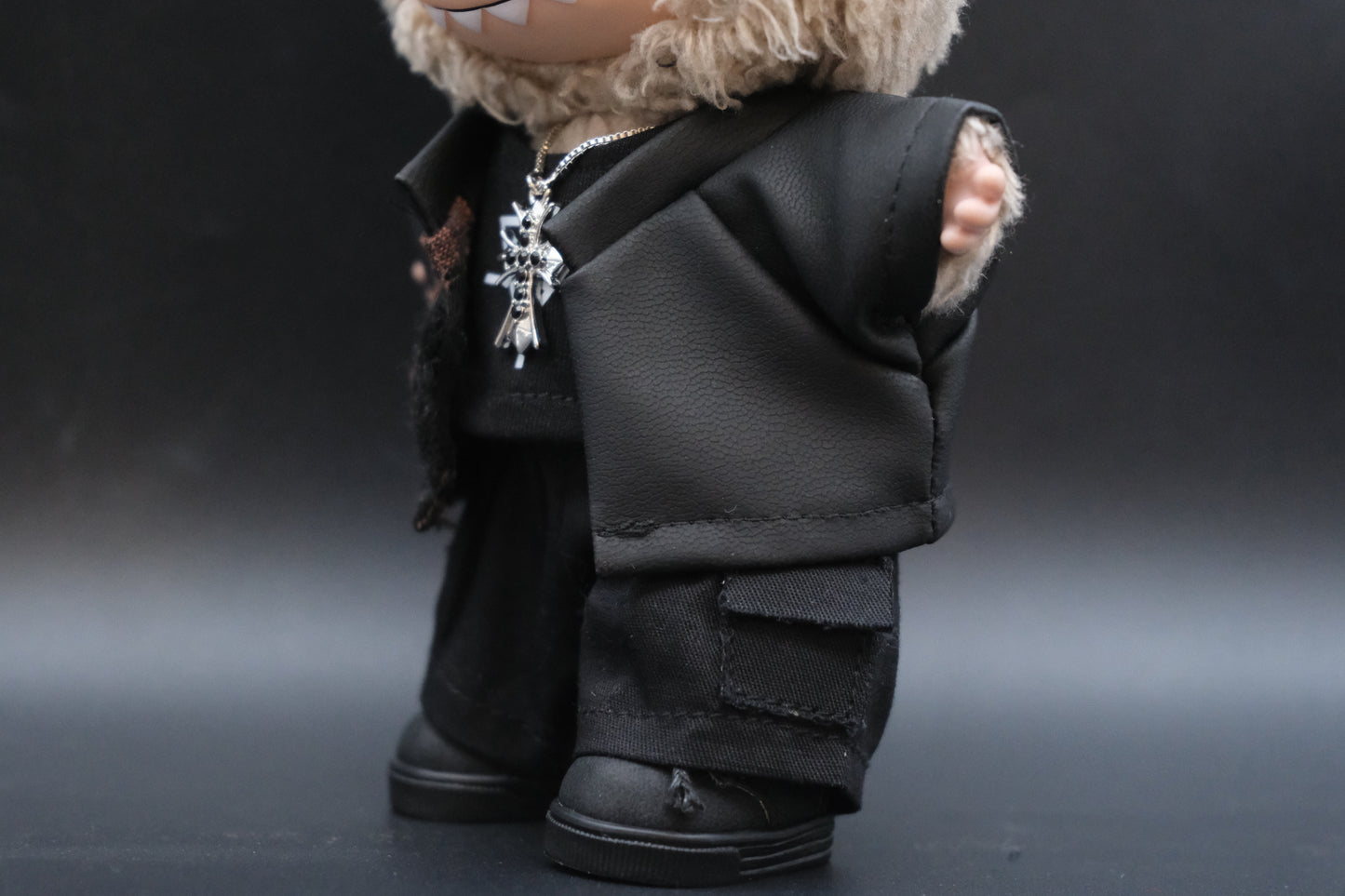 Close-up of a Labubu figure showing the details of the black embossed jacket, black t-shirt, checkered pants, and a unique necklace