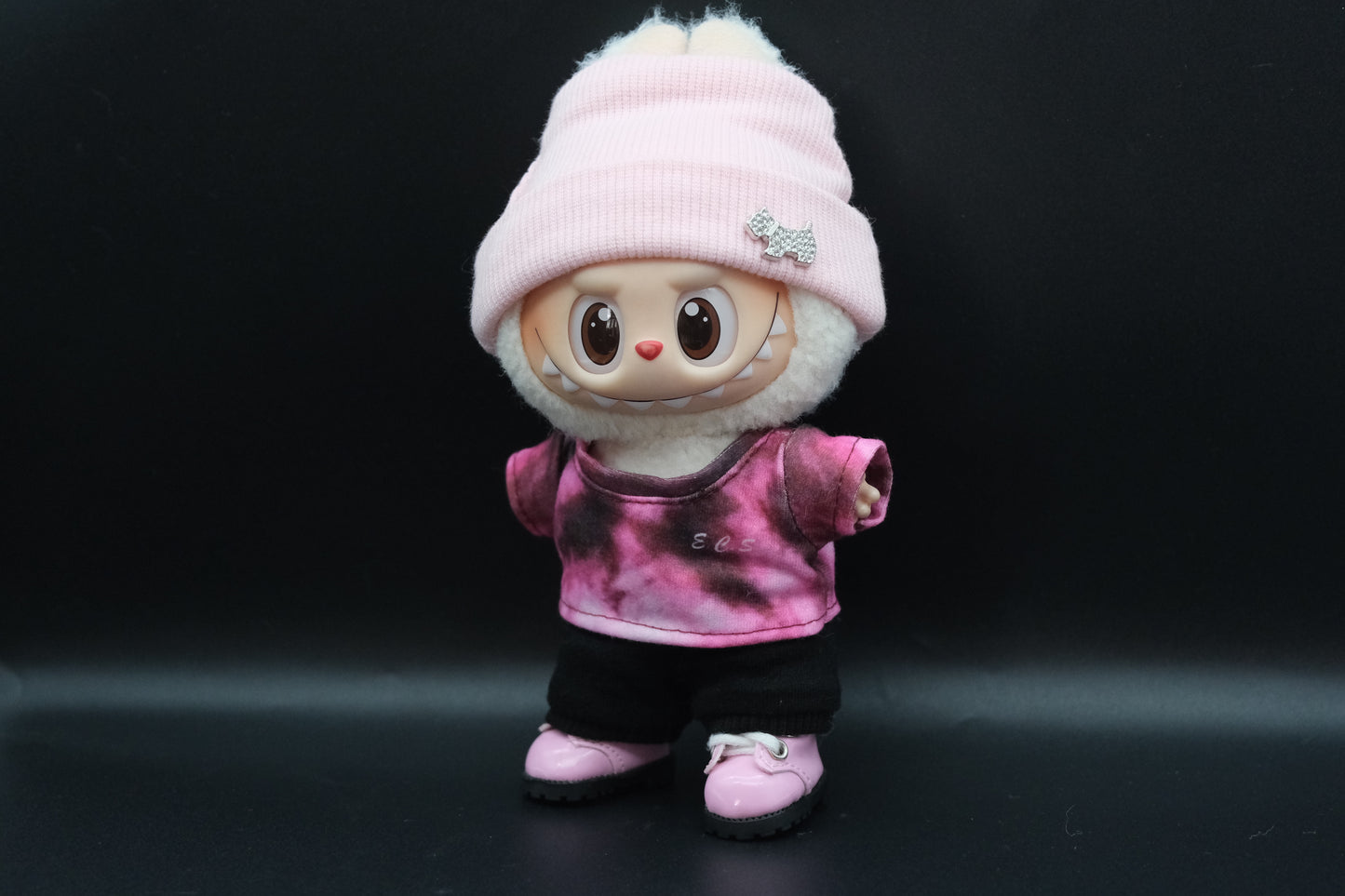 side view of A Labubu figure wearing a red and black color-blocked shirt, pink headband, black pants and pink shoes
