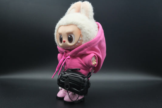 side view of A Labubu figure wearing a pink hoodie, black pants, crossbody bag and pink sneakers.