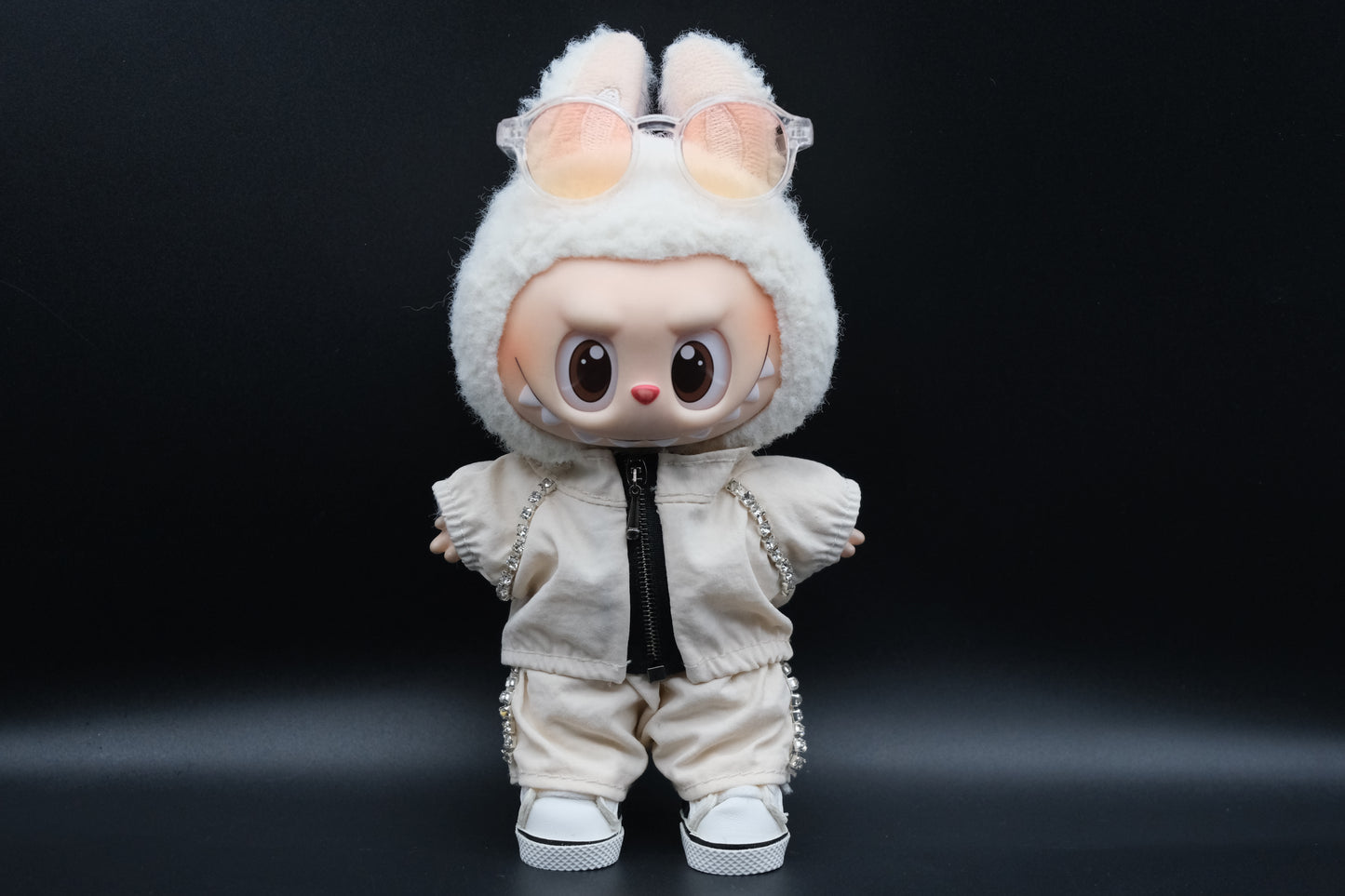 A Labubu figure wearing a white zippered jacket, white pants and and white sneakers.