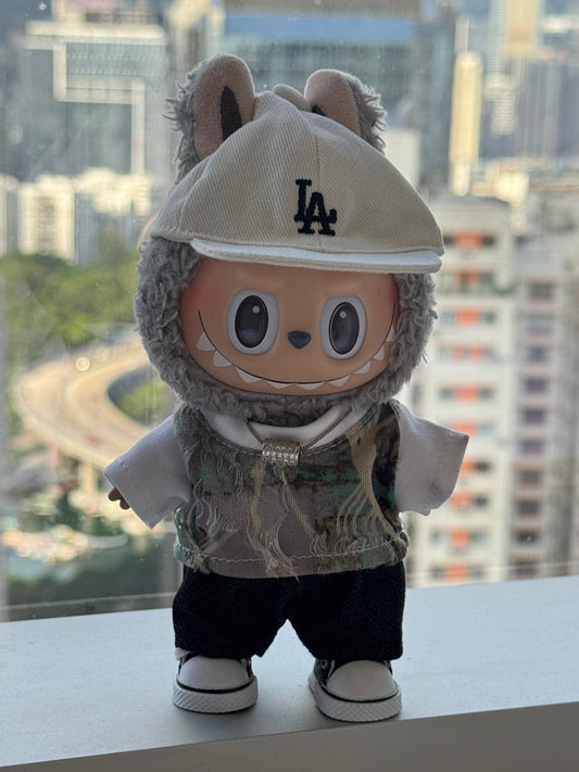 A Labubu figure wearing a 5-piece preppy street style outfit, including a striped t-shirt, light pants, a baseball cap, necklace, and dark shoes.