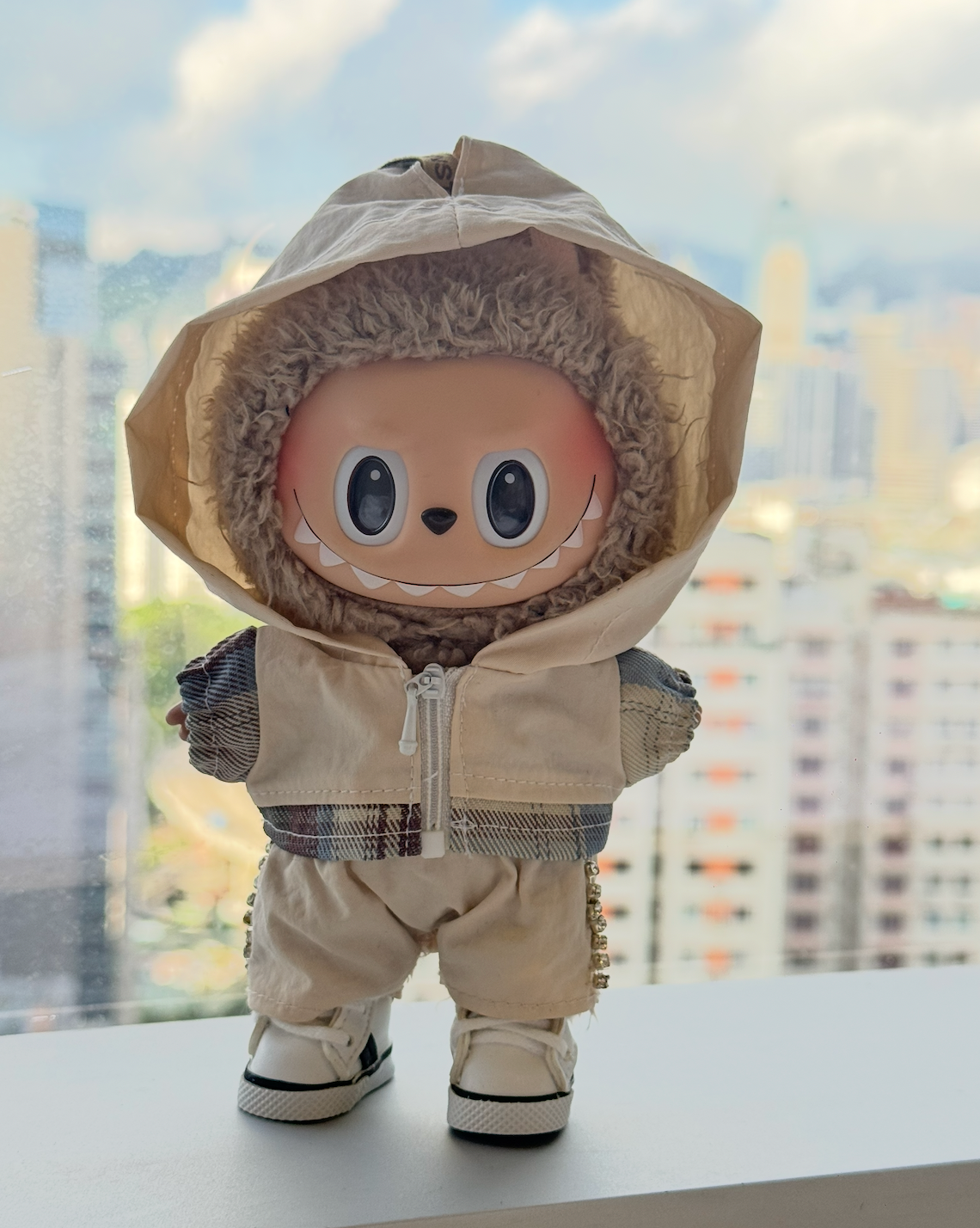A trendy Labubu designer toy figure wearing a minimalist white zip-up hoodie with a contrasting white zipper, white pants, and stylish white high-top sneakers with black accents.