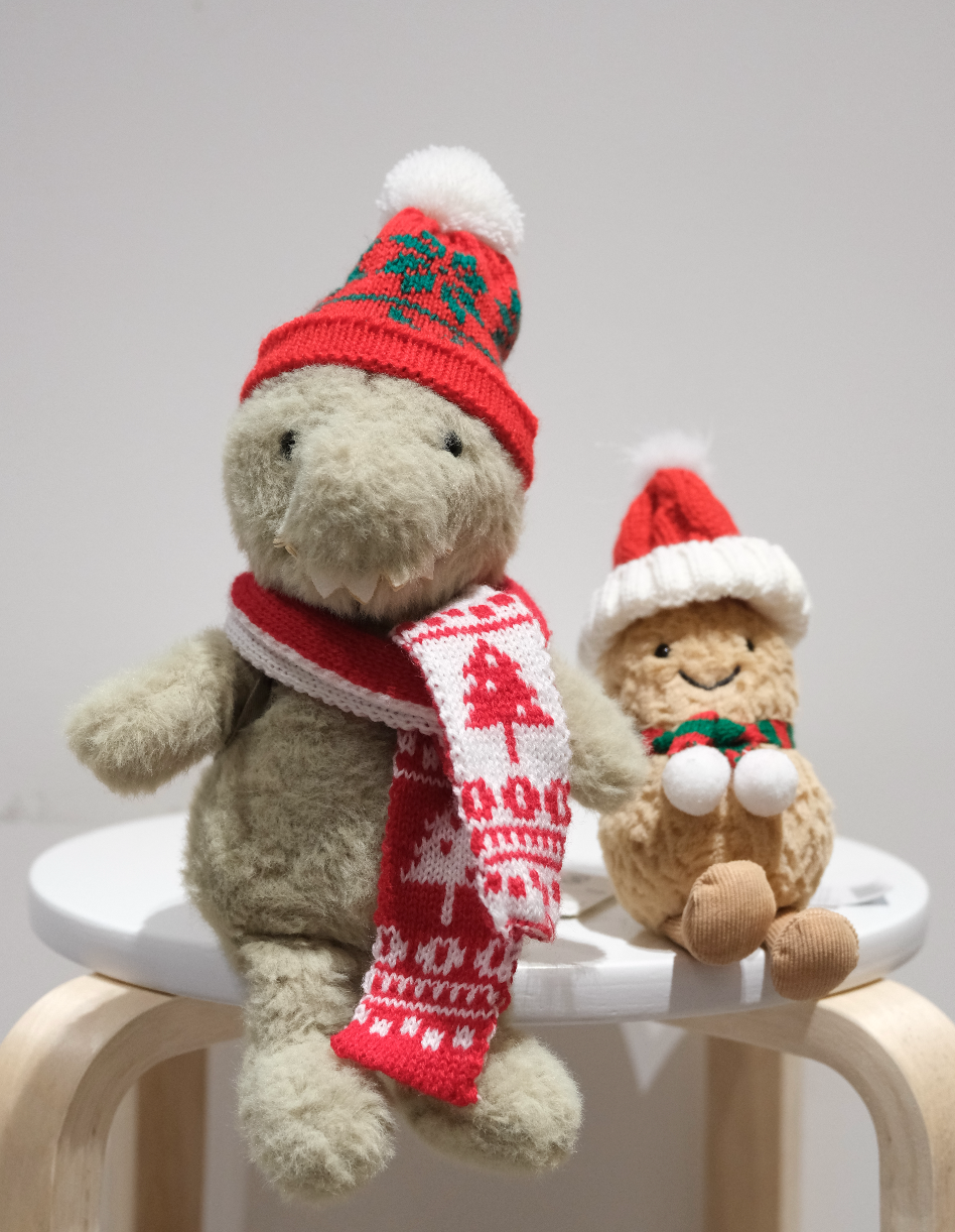 Two-piece festive accessory set for Jellycat Amuseables, featuring a red Santa hat and miniature red scarf laid flat.