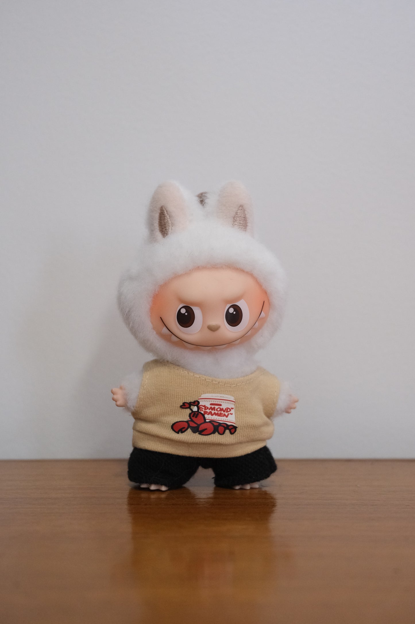 Labubu figure wearing a lobster graphic tank top and black pants.