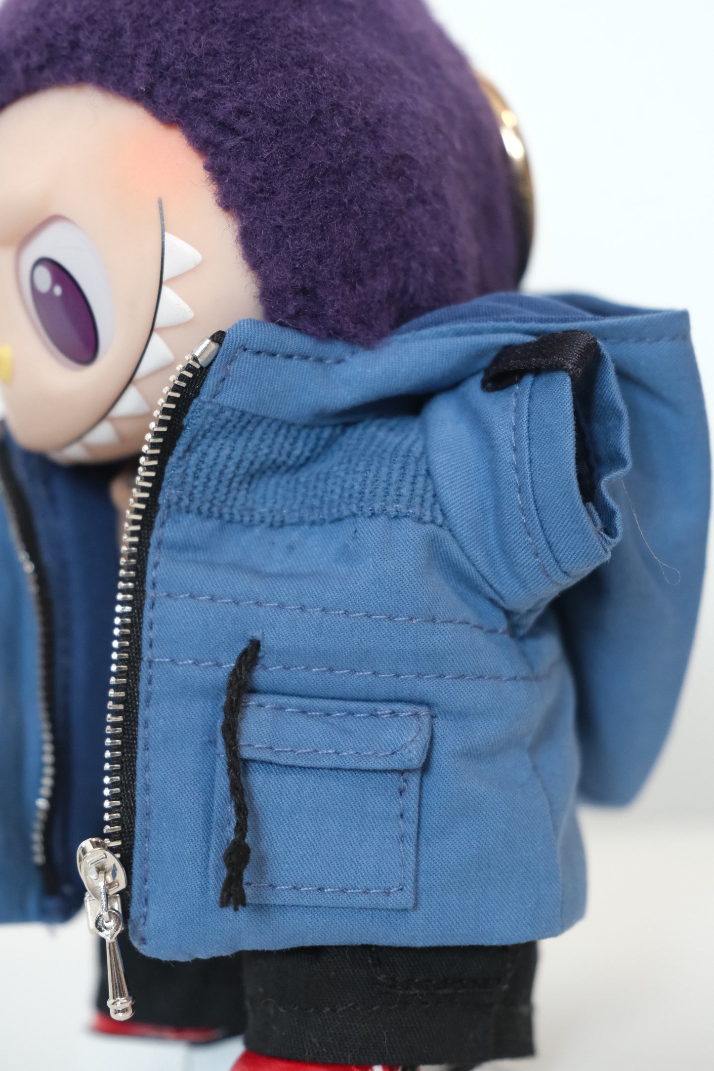Blue jacket with a zipper and a labubu in the background