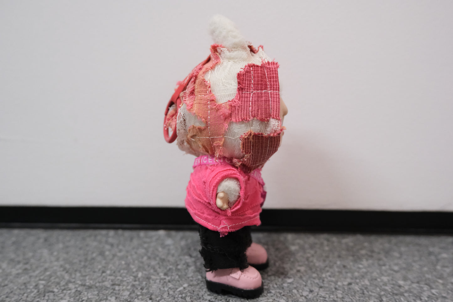 A Labubu figure in a 4-piece pink wasteland outfit, featuring a uniquely textured pink hoodie, black pants, pink shoes, and a small pink crossbody bag.