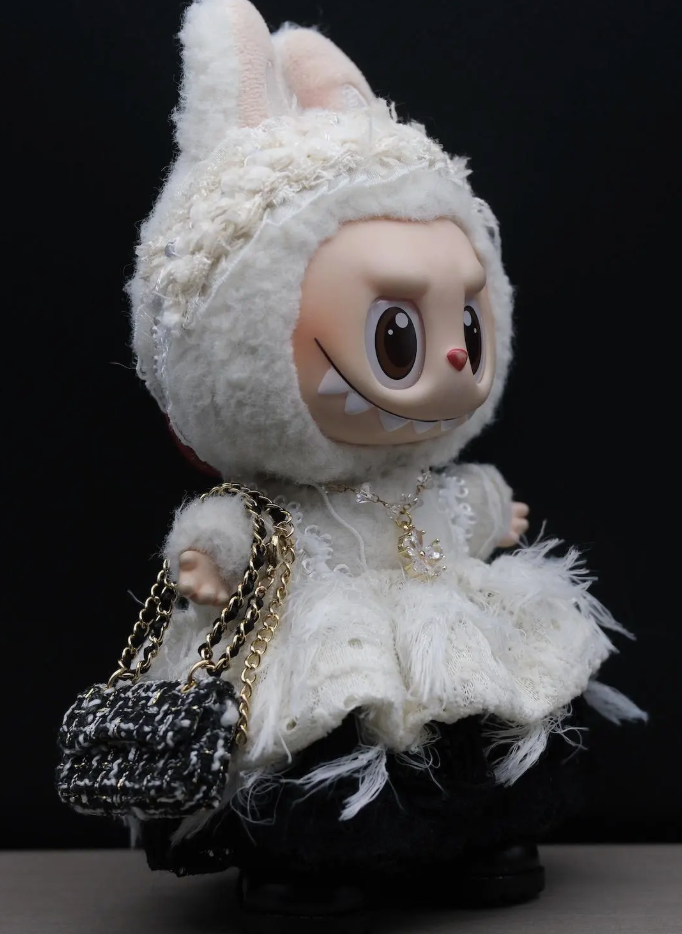 A LABUBU doll wearing a handmade black and white striped dress with a black bow headband.