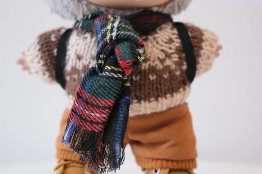 Close-up of The labubu figure's tartan scarf and chunky knit sweater.