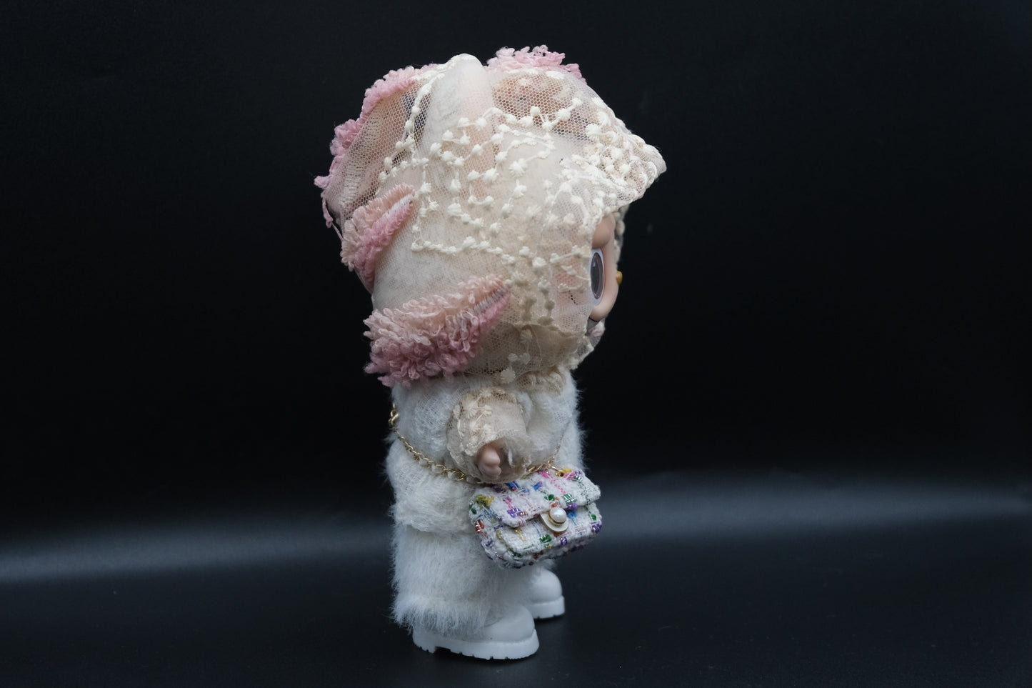 side view of A Labubu figure wearing a white designer hoodie outfit, white pants and shoes, and a crossbody bag