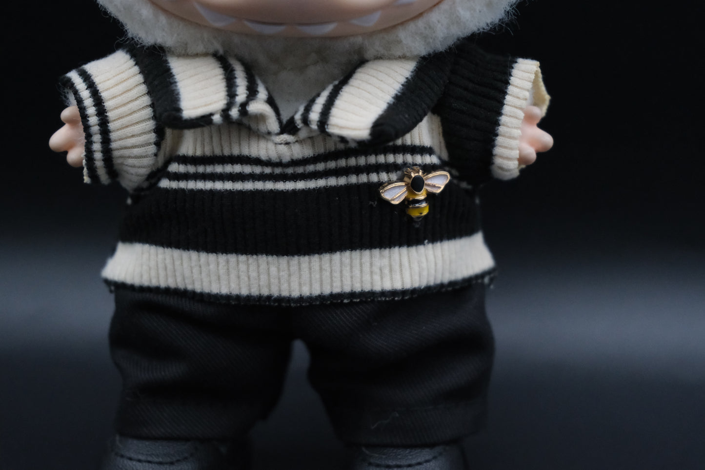 details of A Labubu figure wearing a white and black color-blocked shirt, black pants and black sneakers.