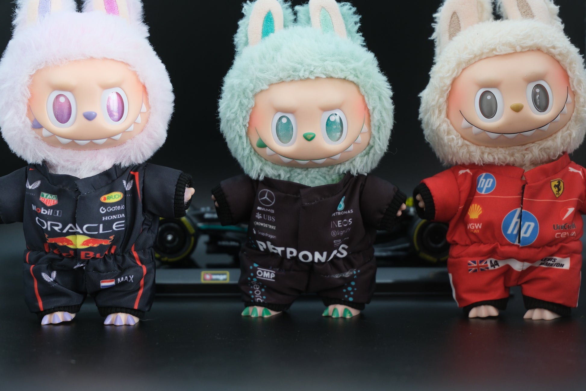 A collection of four LABUBU dolls wearing handmade F1 team uniforms from Mercedes, Ferrari, and Red Bull Racing.