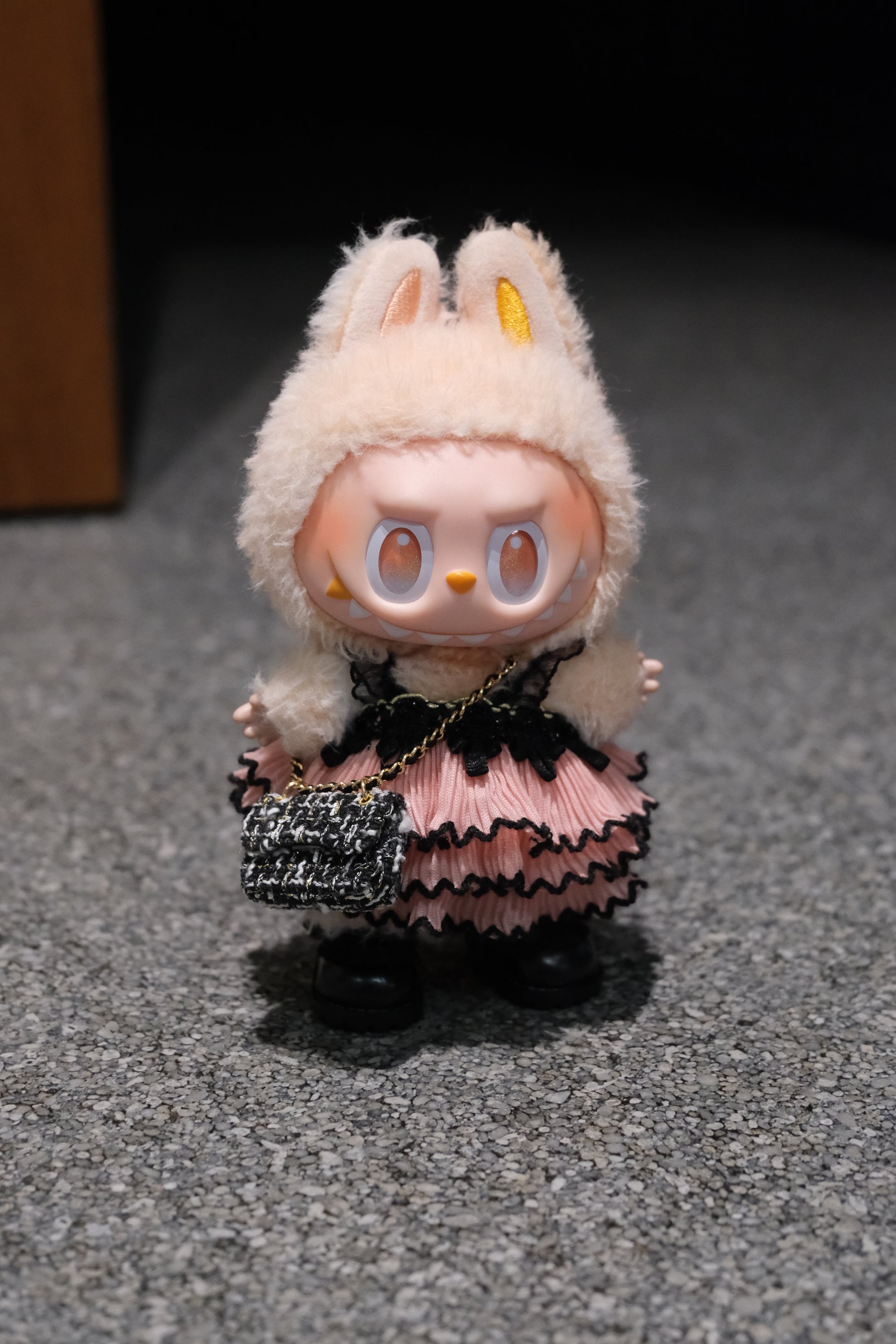 A Labubu figure wearing a 3-piece gothic lace dress outfit, featuring a black pink dress  a black chain strap bag, and black shoes.