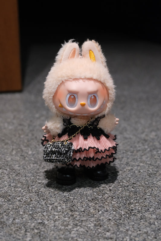 A Labubu figure wearing a 3-piece gothic lace dress outfit, featuring a black pink dress  a black chain strap bag, and black shoes.