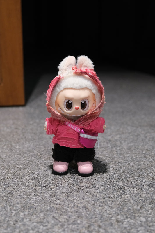 A Labubu figure in a 4-piece pink wasteland outfit, featuring a uniquely textured pink hoodie, black pants, pink shoes, and a small pink crossbody bag.
