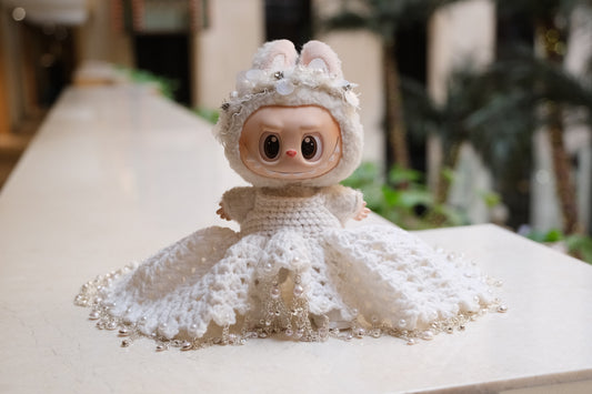 A Labubu figure wearing a white wedding dress with a lace bodice, full skirt, and a headband.

