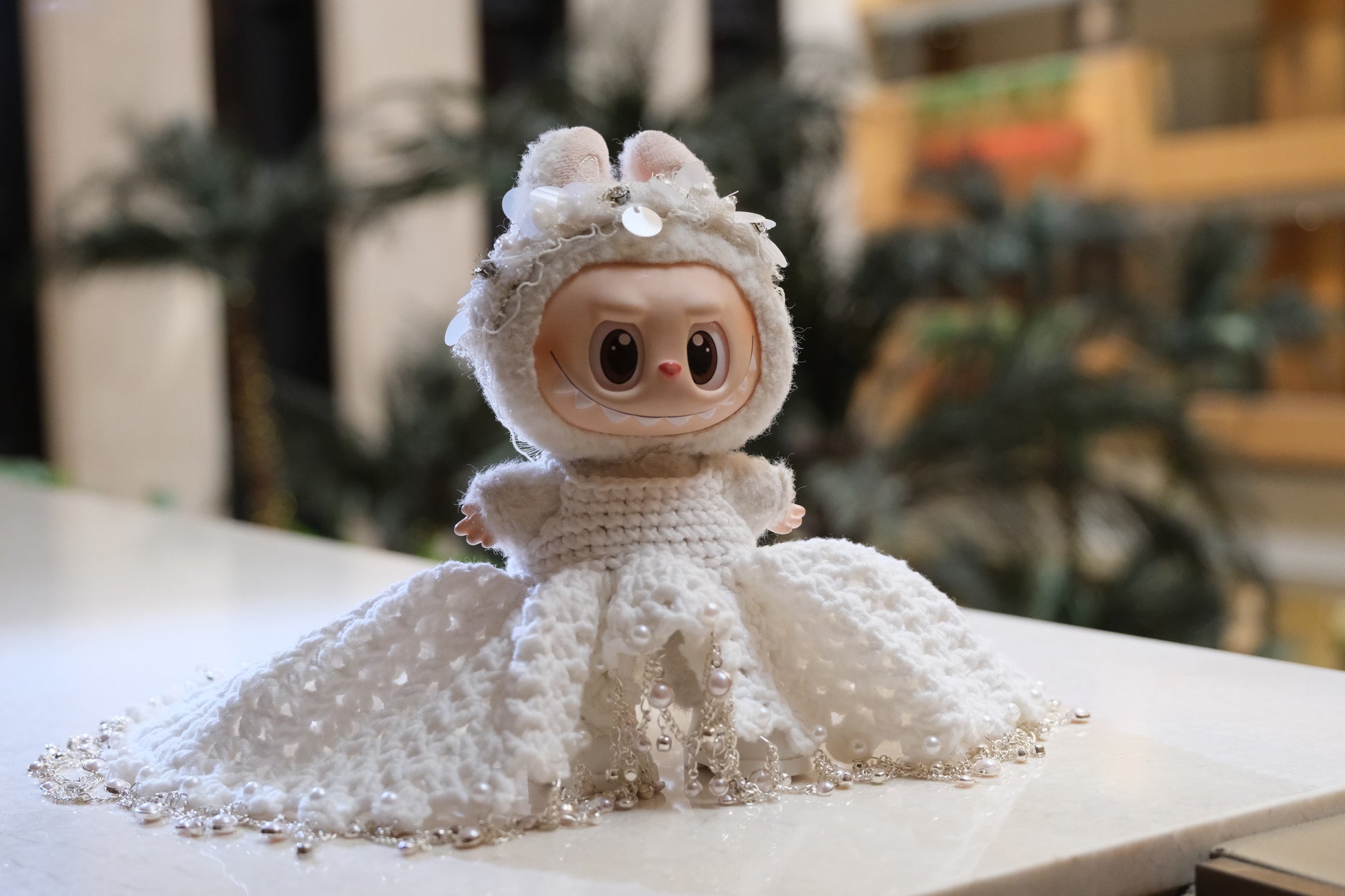 A Labubu figure wearing a white wedding dress with a lace bodice, full skirt, and a headband.

