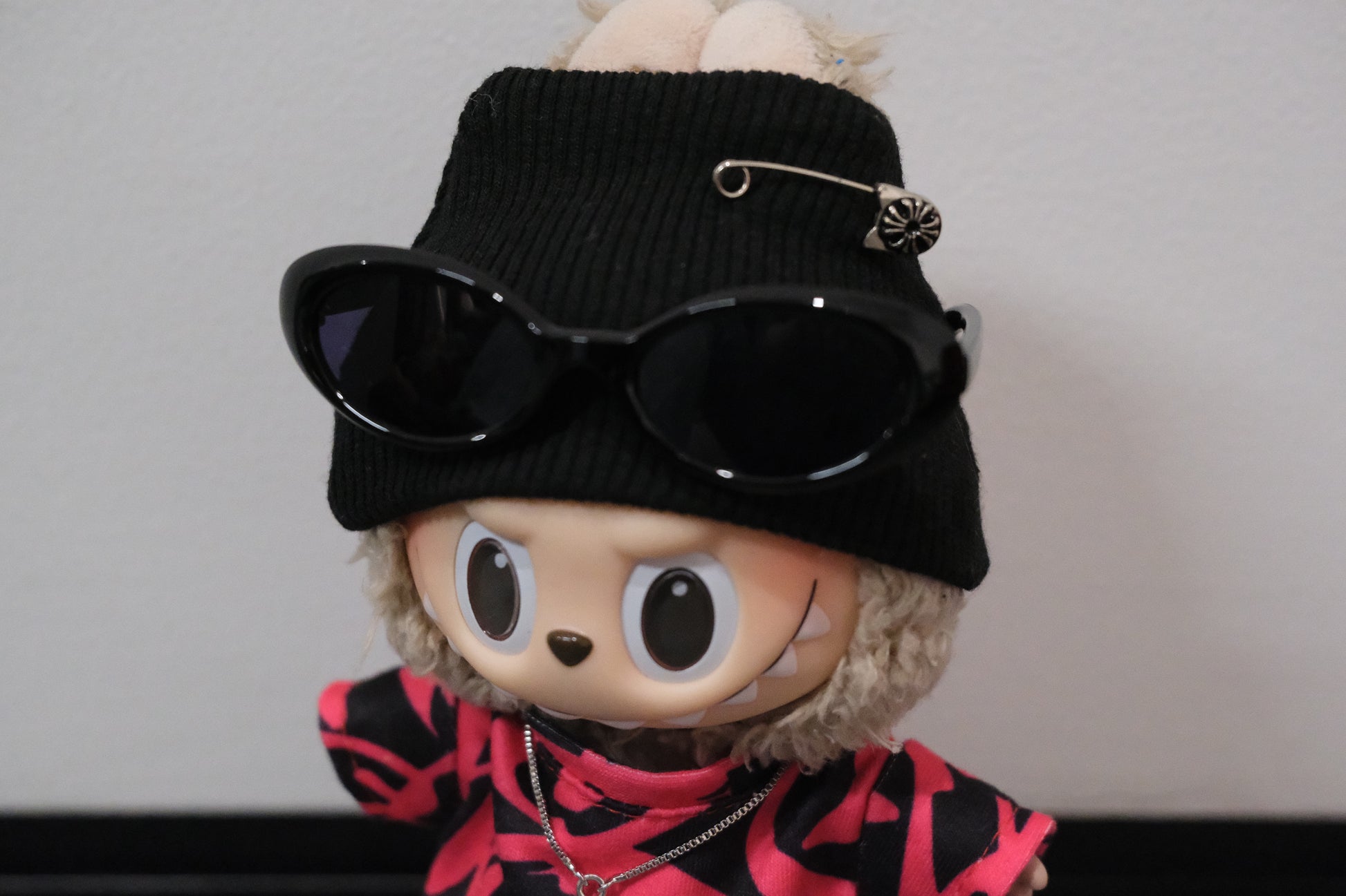 labubu wearing a black beanie with sunglasses and a pink and black outfit 
