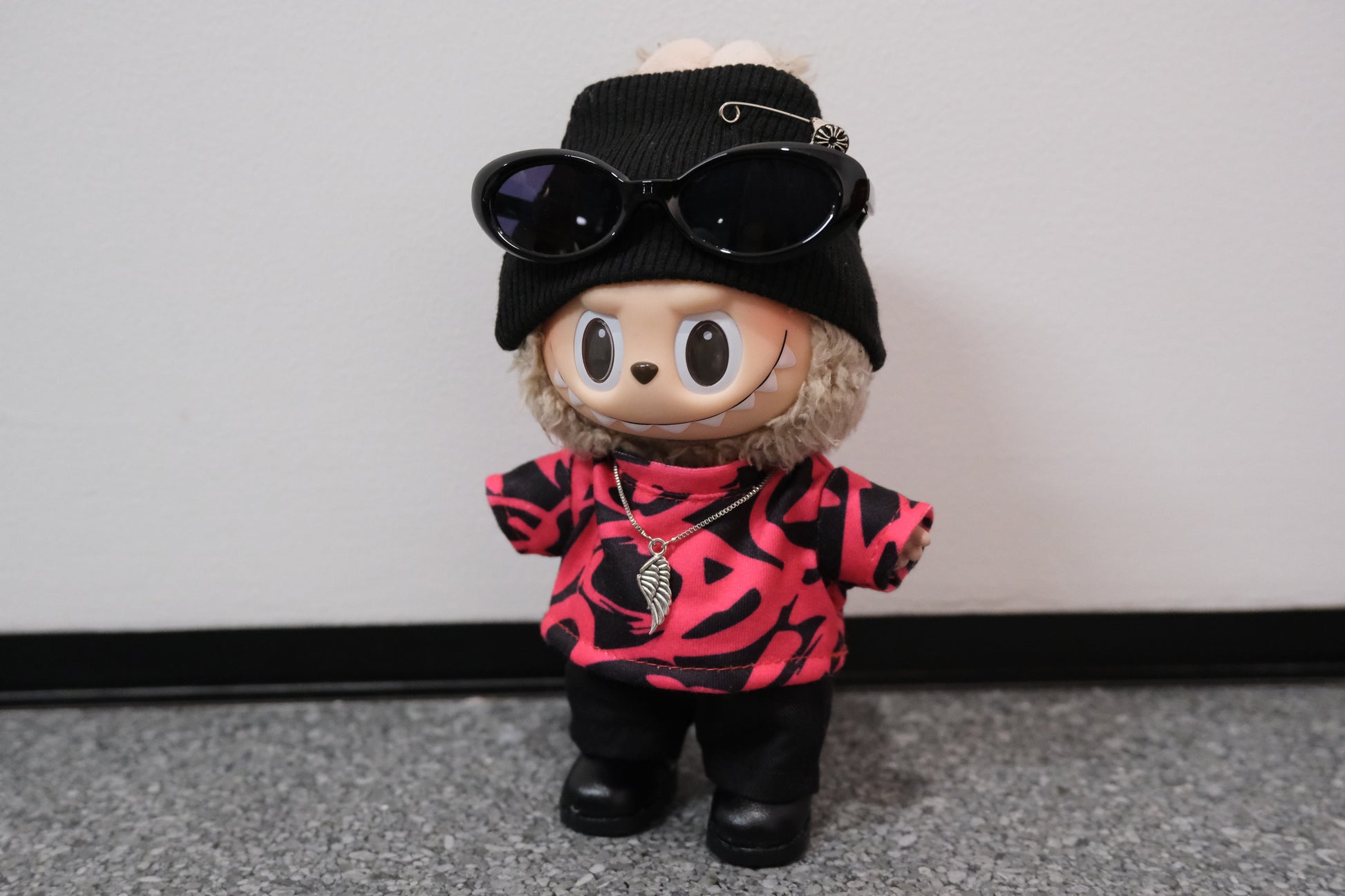 Toy figure wearing sunglasses, black hat, and pink and red patterned shirt