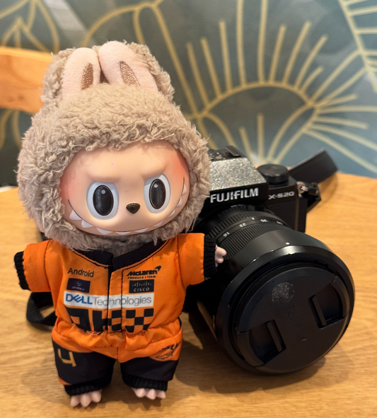 A Labubu figure wearing a black and orange McLaren F1 racing jumpsuit.