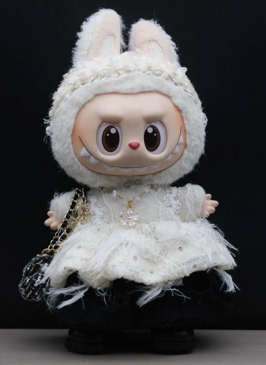 Labubu in a white outfit with a hood and dress, holding a small handbag against a black background.