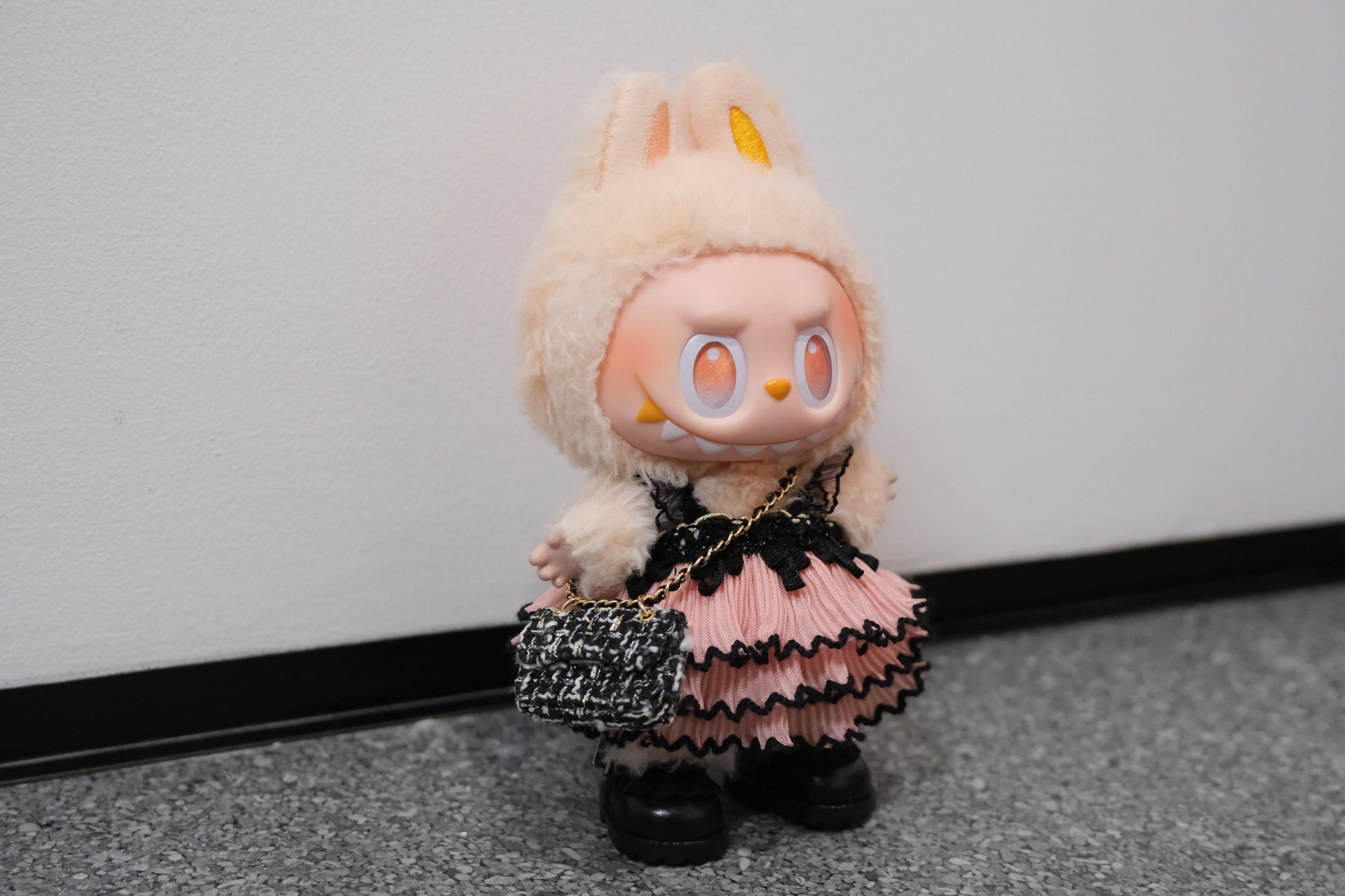 A Labubu figure wearing a 3-piece gothic lace dress outfit, featuring a black pink dress  a black chain strap bag, and black shoes.