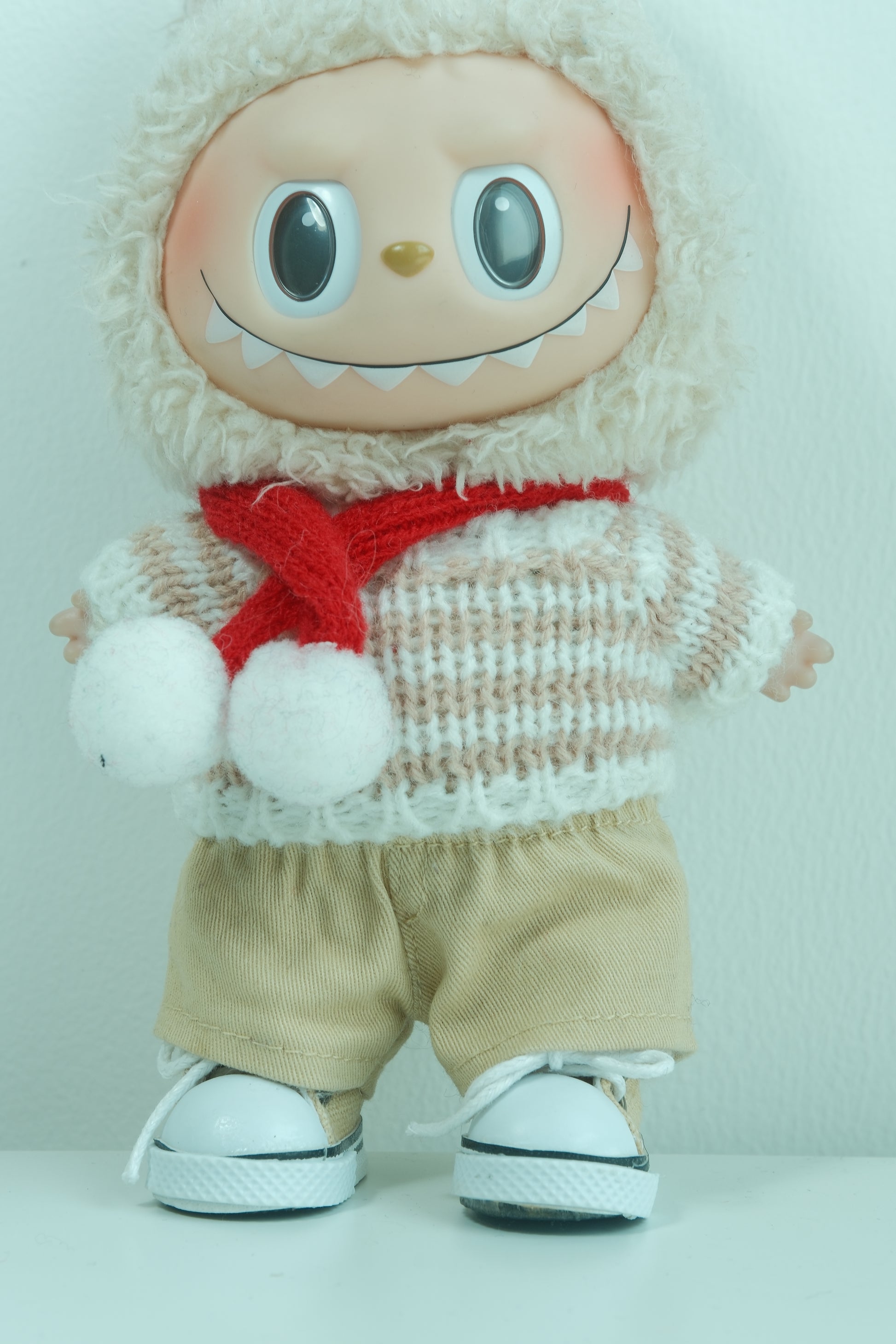 Close-up of The Monsters figure in the chunky knit sweater and layered plaid scarf