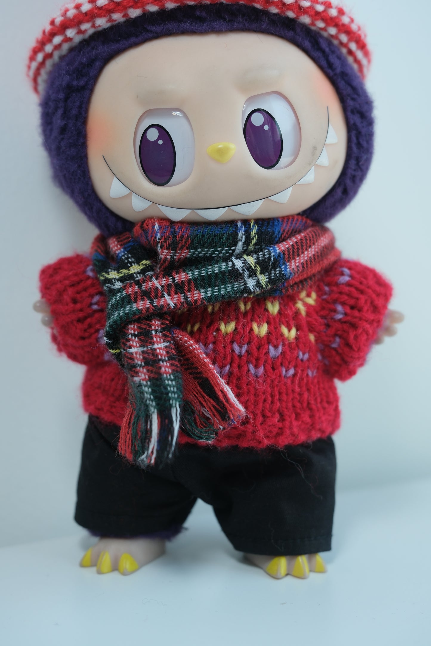 Close-up of The Monsters figure in the festive red knit sweater and traditional tartan scarf