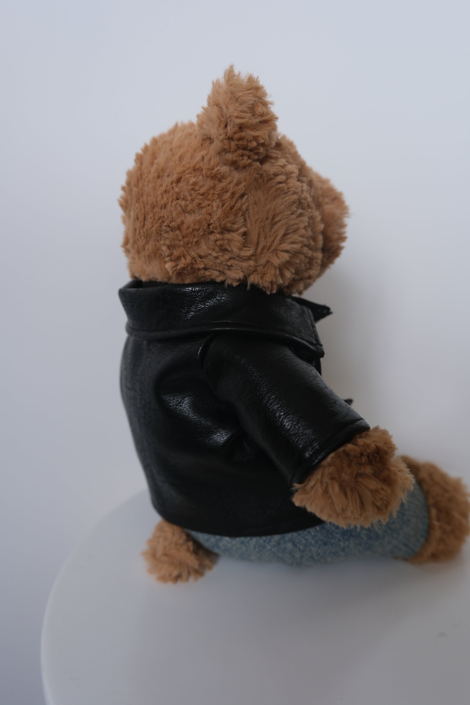 Jellycat Bartholomew Bear wearing a 3-piece punk outfit including a black leather jacket, black sweater, and denim jeans.