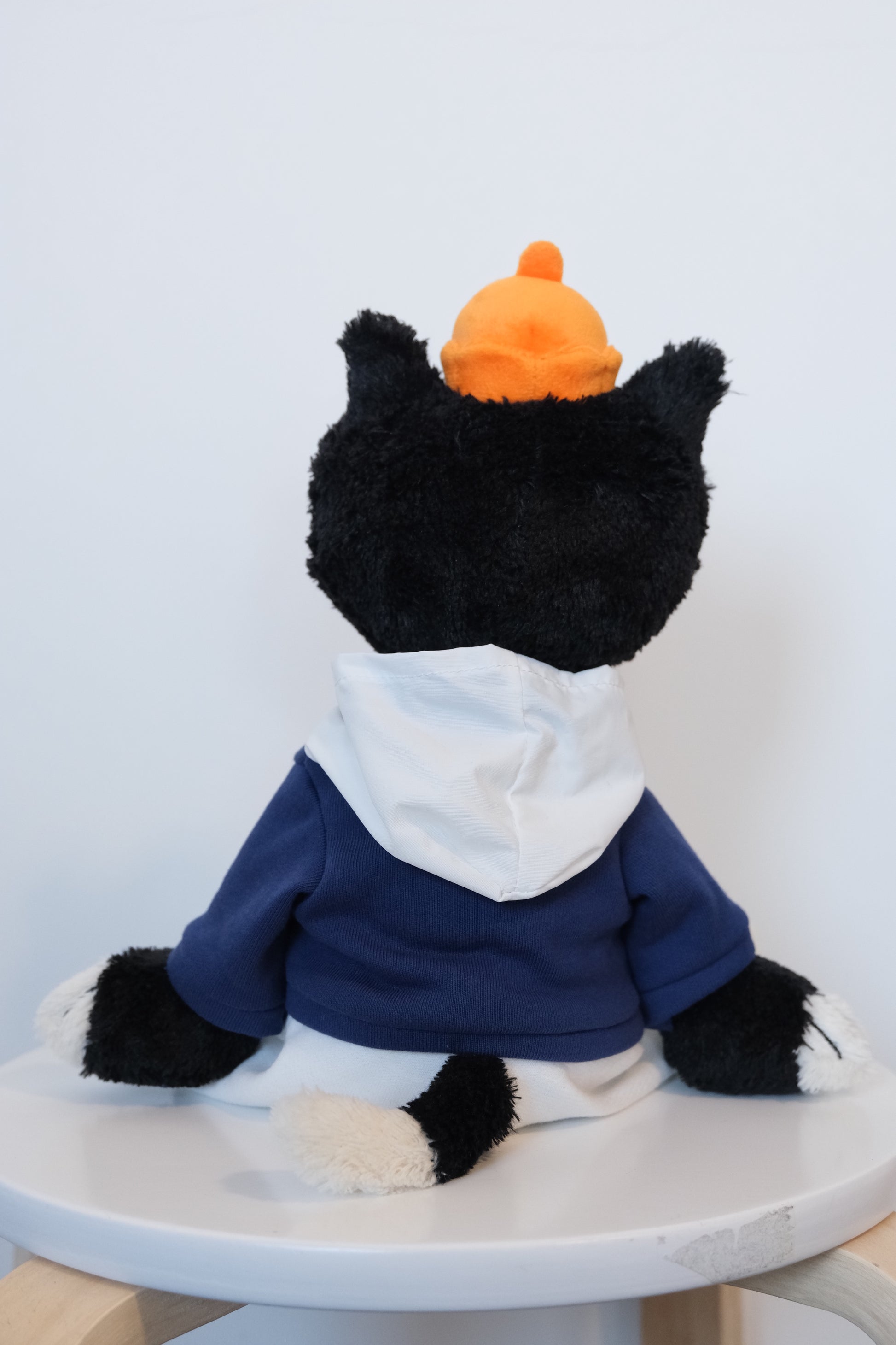 back view of Jellycat Jack mascot cat plush wearing a blue streetwear hoodie and high-contrast white pants