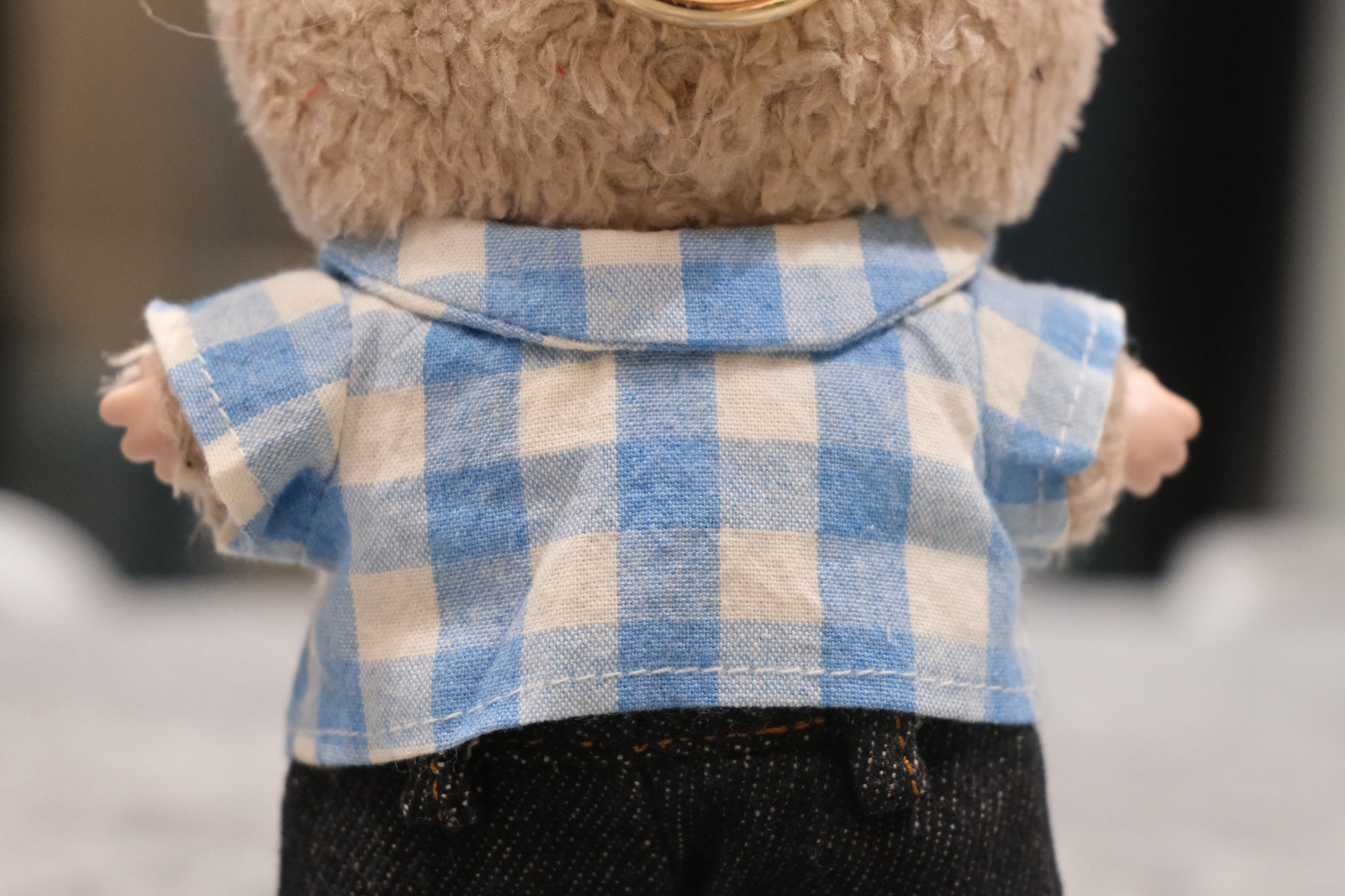 Close-up of The Monsters figure's blue and white gingham shirt with a red button and dark shorts