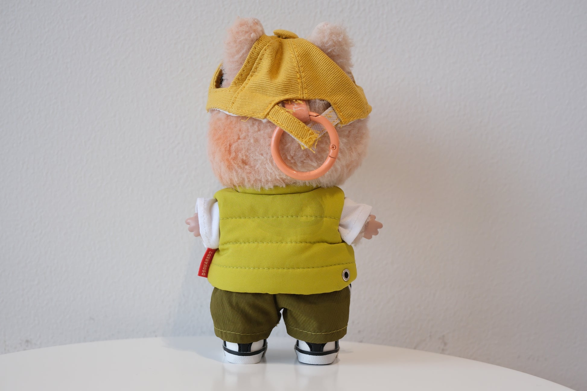 back view of labubu in a yellow cap, green vest, and dark green  shorts 