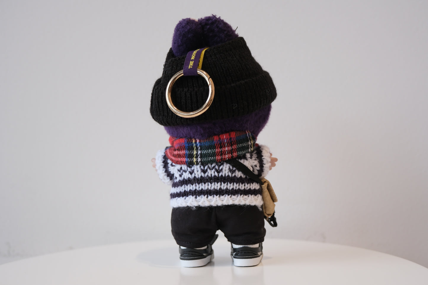 back view of Labubu figure wearing a 6-piece winter streetwear outfit, including a striped knit sweater and black beanie
